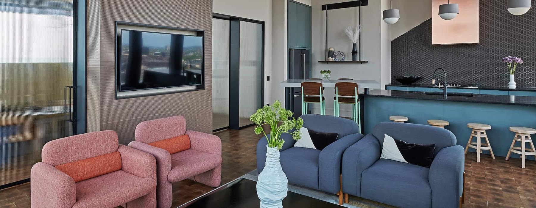 a living room with a blue couch and pink chairs